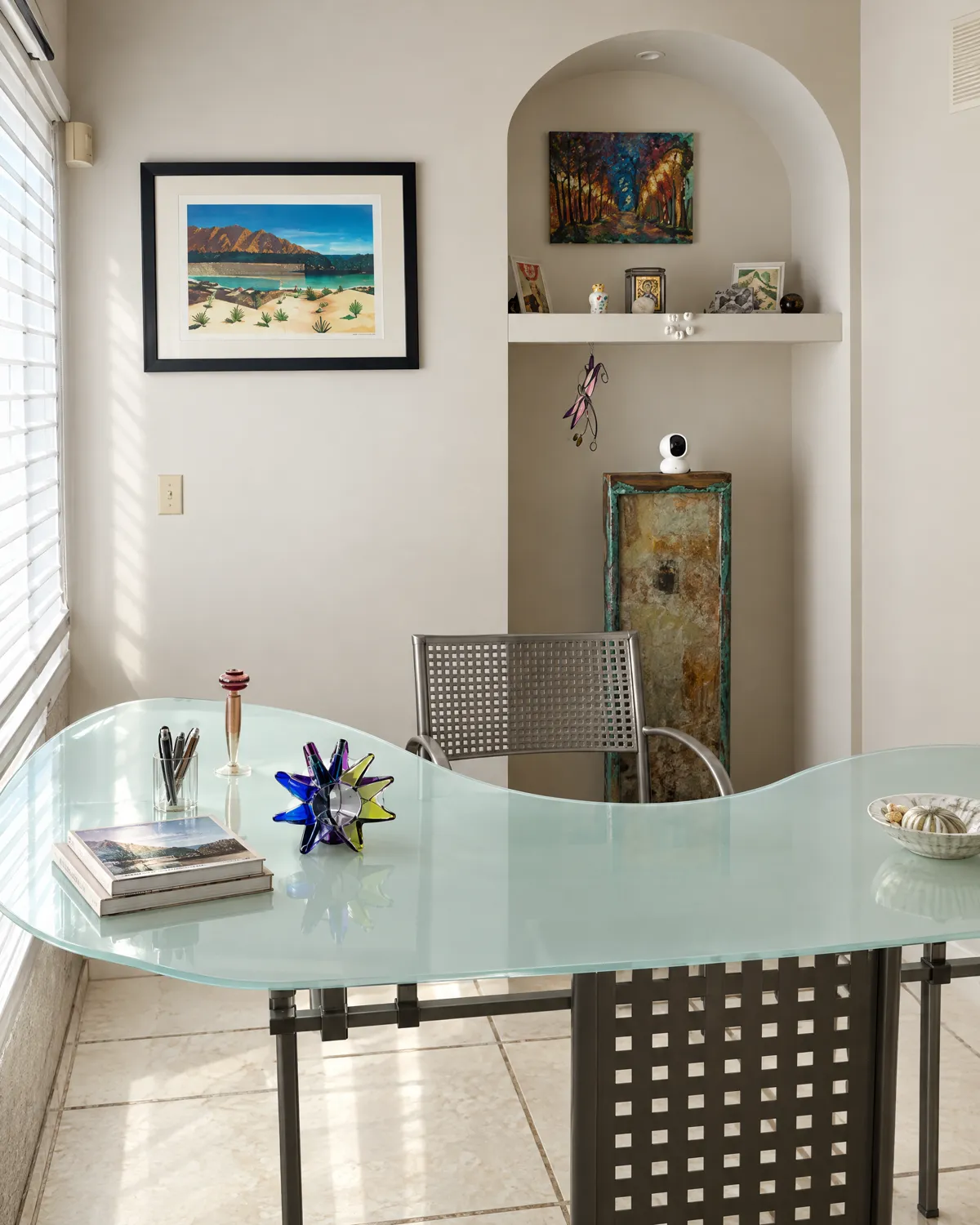 Reception: curved glass desk, arched niche with a painting and a framed landscape